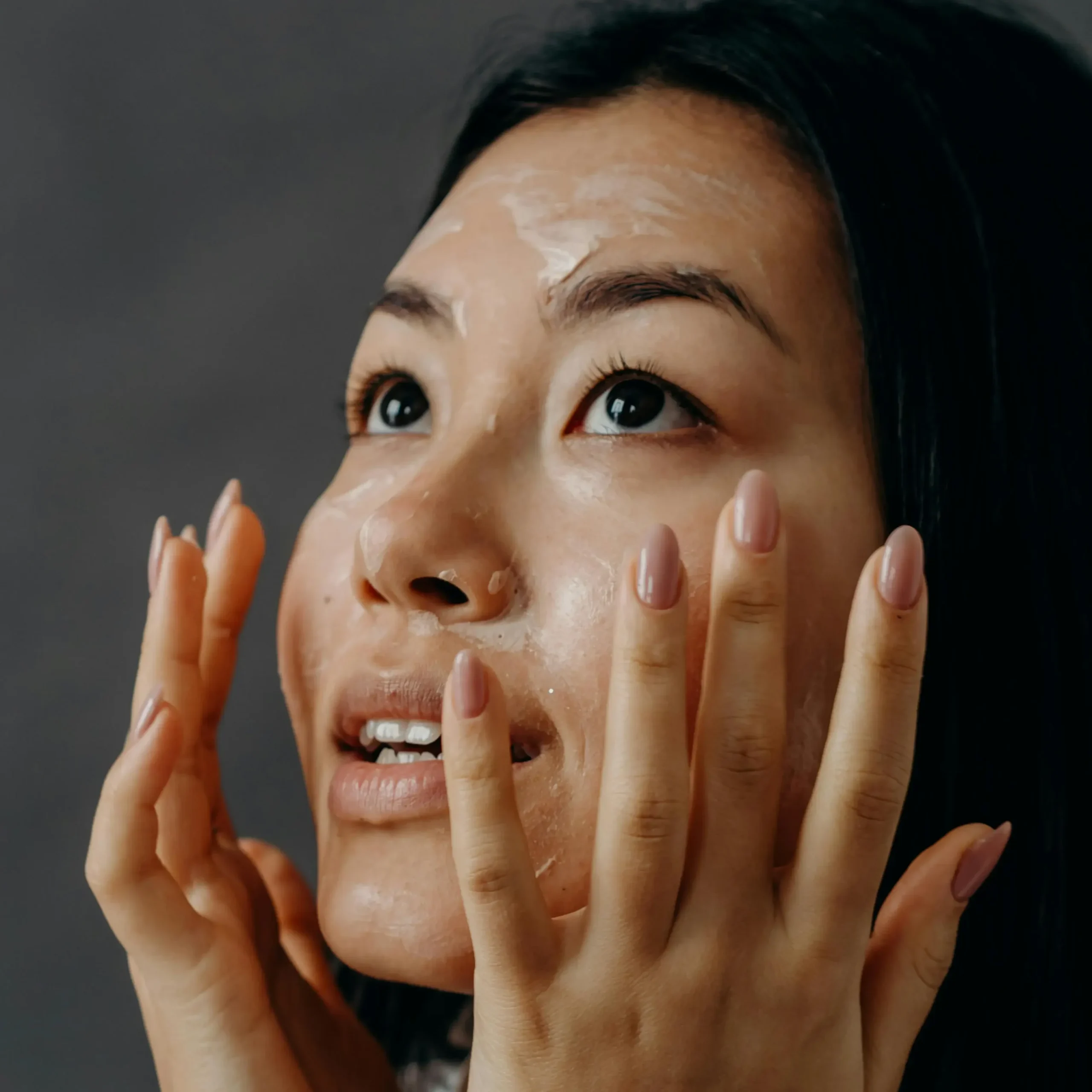 Mujer adulta utilizando una crema antiarrugas compatible en la piel acneica.