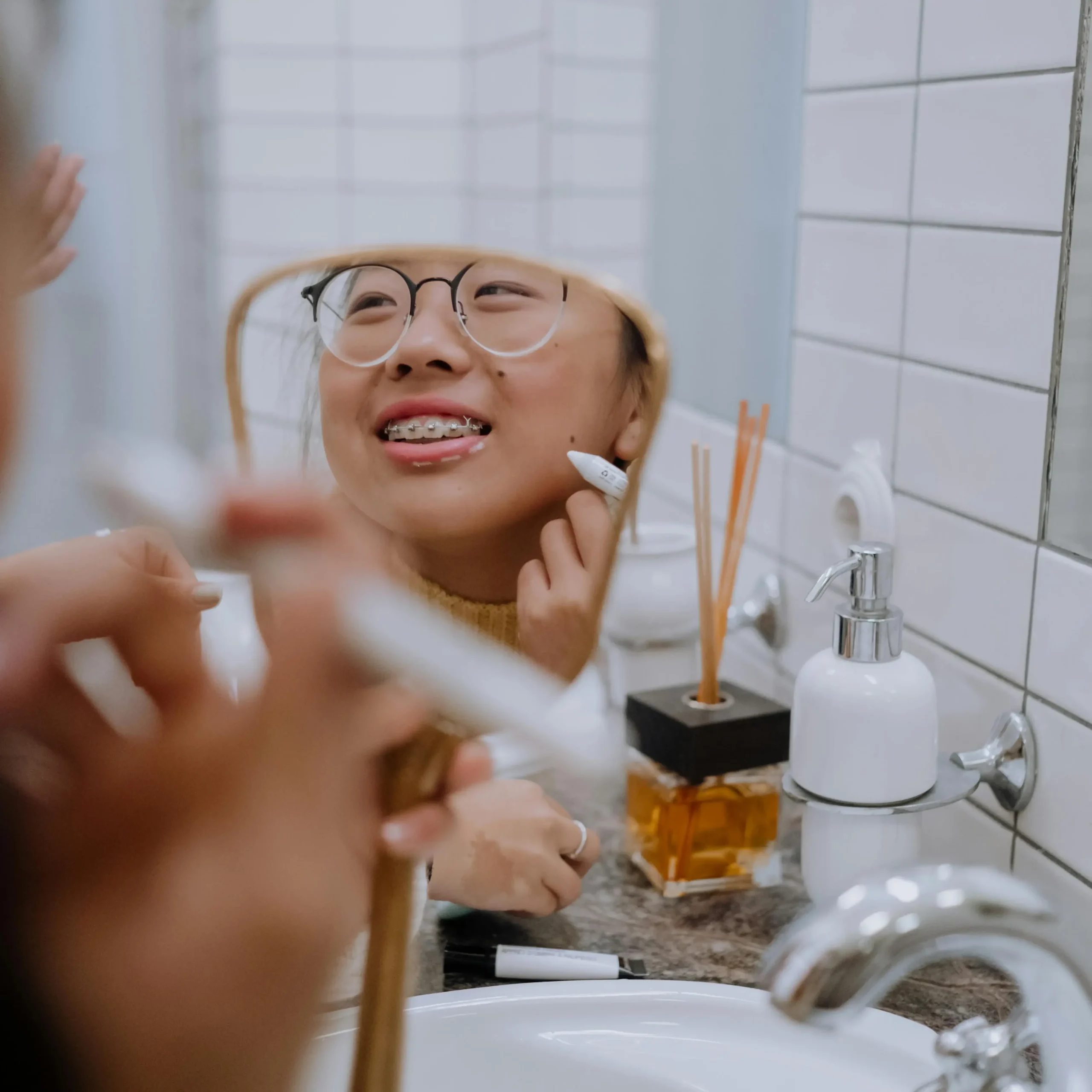 Chica joven aplicando una crema para secar granos localizados en la cara.