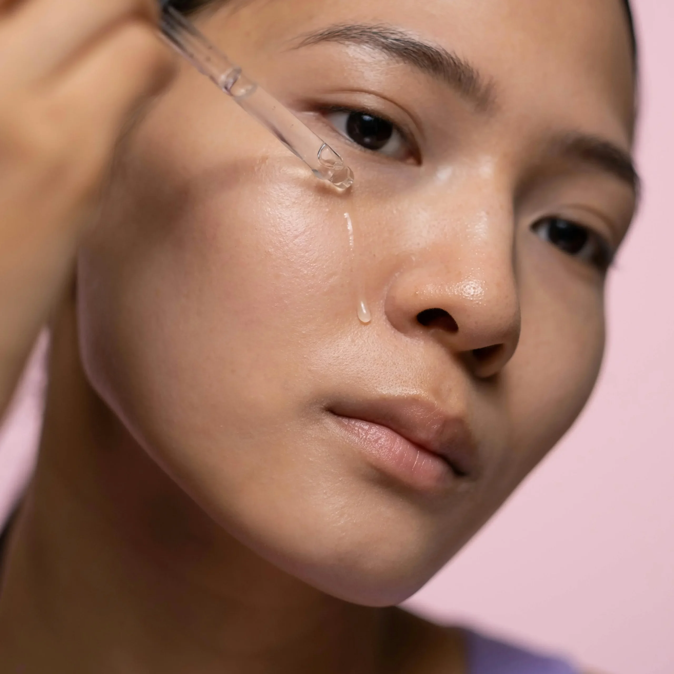 Mujer adulta morena aplicando un sérum con retinol para quitar el acné.